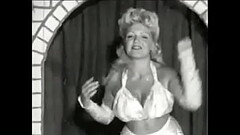 Curly blonde with huge tits takes part in an erotic performance of the 60s Thumb